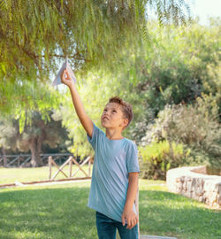 Side view of young woman with arms raised standing on field