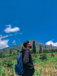 Woman standing on mountain against blue sky