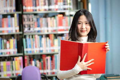 Portrait of a smiling young woman reading book