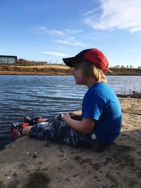 A little boy sits at the edge of a pond waiting to see some ducks