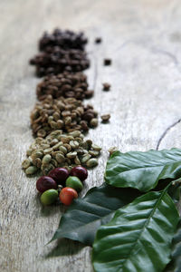 Close-up of various roasted coffee beans with leaves on table