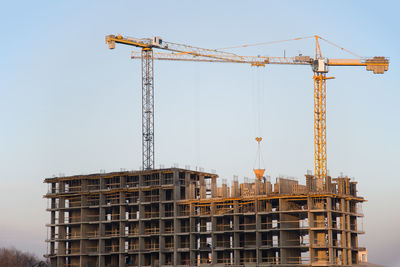 Crane by building against sky