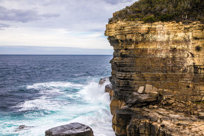 Rock formation on sea shore against sky