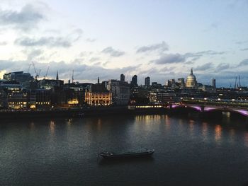 View of city at waterfront against cloudy sky