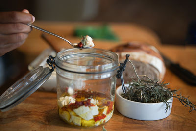 Close-up of hand holding glass jar on table