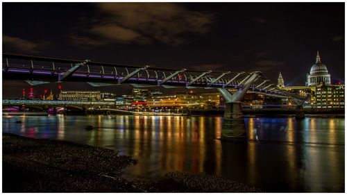 Bridge over river in illuminated city at night