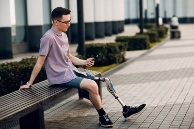 Side view of young man using mobile phone while sitting on seat