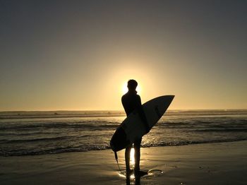 Silhouette man on beach against sky during sunset