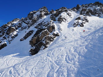 Distant view of person skiing on snow covered rocky mountain