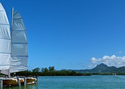 Sailboat moored on lake against blue sky