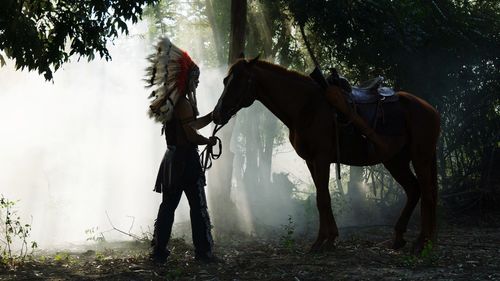 Man with horse standing in forest