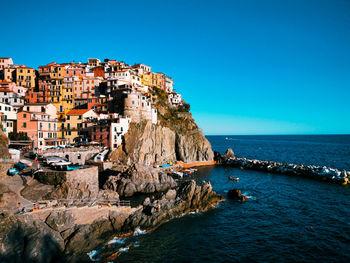 Scenic view of sea by buildings against clear blue sky