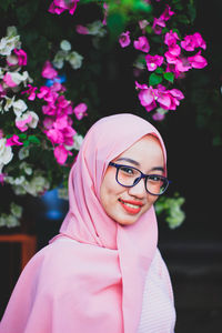 Portrait of smiling young woman with pink hair standing against plants