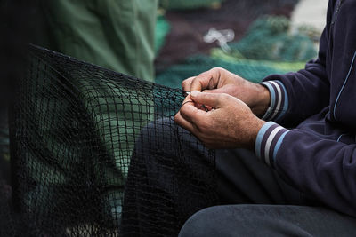 Cropped image of hand weaving fishing net