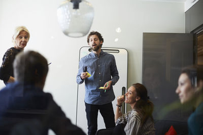Businessman and businesswoman giving presentation to colleagues in board room at creative office