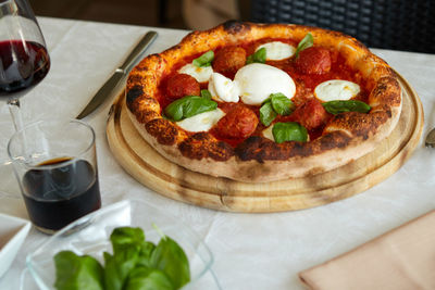 Cropped hand of person holding pizza on table