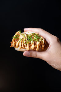 Close-up of hand holding food against black background