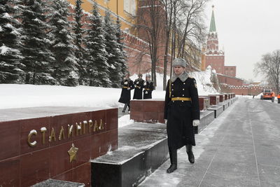 Rear view of people walking on snow covered city