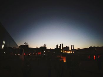 Silhouette of factory against clear sky at night