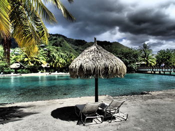 Palm trees on beach against cloudy sky