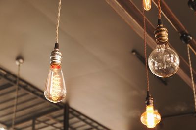 Low angle view of illuminated light bulbs hanging from ceiling