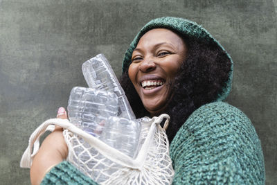 Happy woman holding plastic water bottles in mesh bag