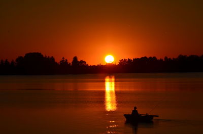 Silhouette man on boat against sky during sunset