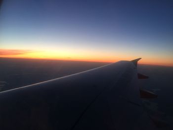 Airplane wing against sky during sunset