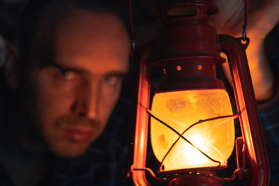 Close-up portrait of young man in illuminated mirror