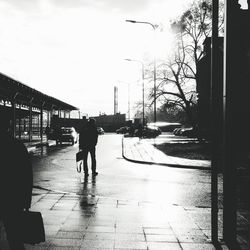 Man walking on wet road in city