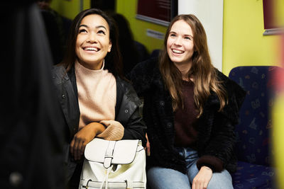 Smiling female friends sitting in train