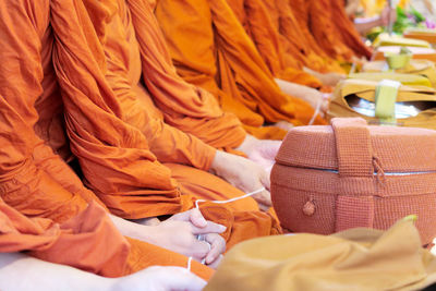 Midsection of monks with container sitting in row