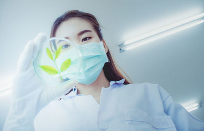 Low angle view of scientist analyzing leaves in petri dish against ceiling