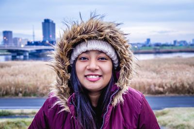 Portrait of smiling young woman against sky