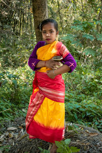 Portrait of young woman standing in forest