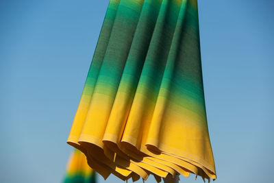 Low angle view of yellow flag against clear blue sky