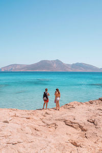 Women standing on beach against clear sky