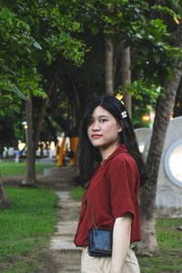 Young woman standing against trees