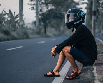 Side view of man sitting on road