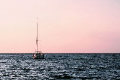 Sailboat sailing on sea against sky during sunset