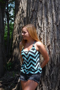 Young woman leaning on tree trunk