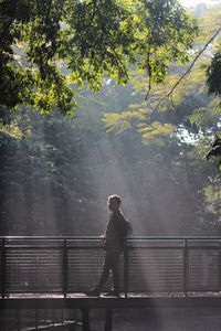 Man standing by railing against trees