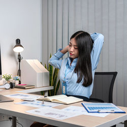 Young businesswoman reading book while sitting at office