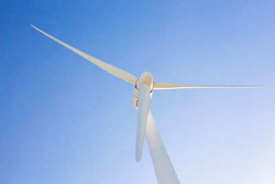 Low angle view of wind turbine against blue sky