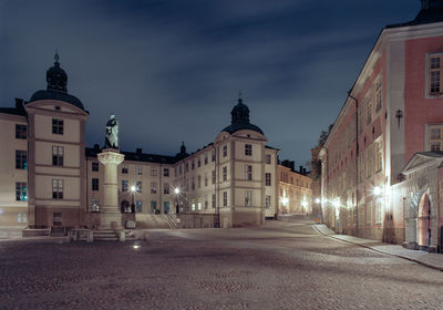 Street amidst buildings against sky at dusk