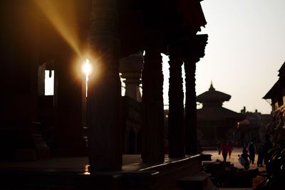 Illuminated street amidst buildings against sky in city