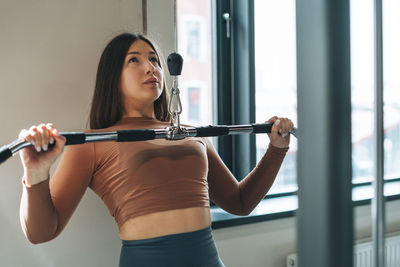 Young fitness brunette woman training for back muscles equipment at the gym