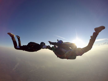 Sunset skydiving. 3-way skydive formation. free-fall man group jumping against clear sky.