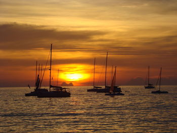 Sailboat sailing on sea against orange sky