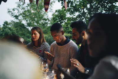 Multi-ethnic male and female friends spending leisure time together during dinner party